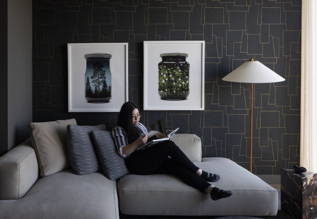 Woman reads a book on the sofa in her den in her apartment