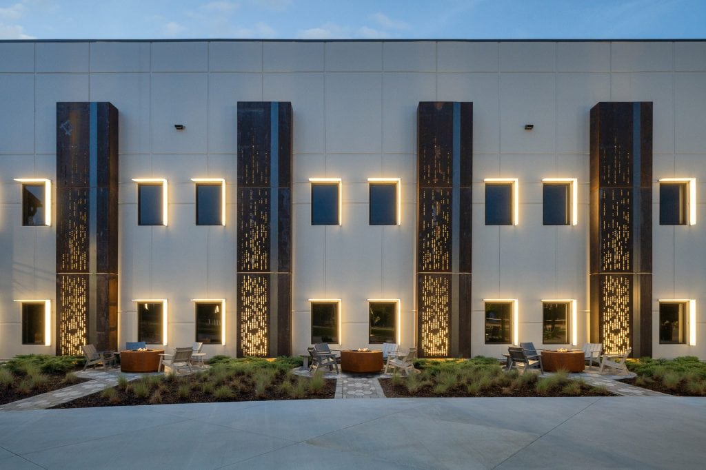 Backlit pillars featuring bible verses in morse code with fire pits in the foreground