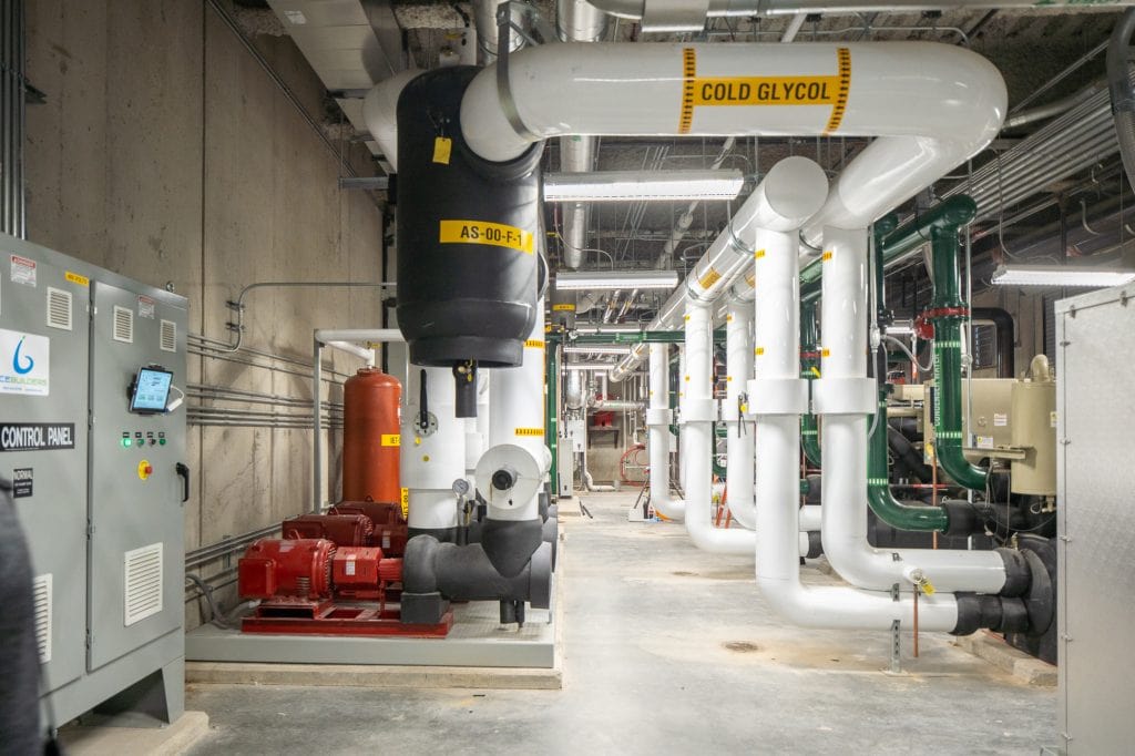 A coolant system for a hockey arena. Massive white, black, red, and green pipes snake through a large room.