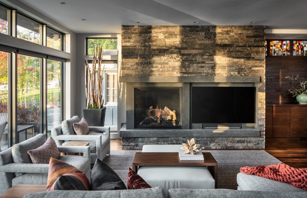 Living room with a stone fireplace, large windows, and modern furniture.